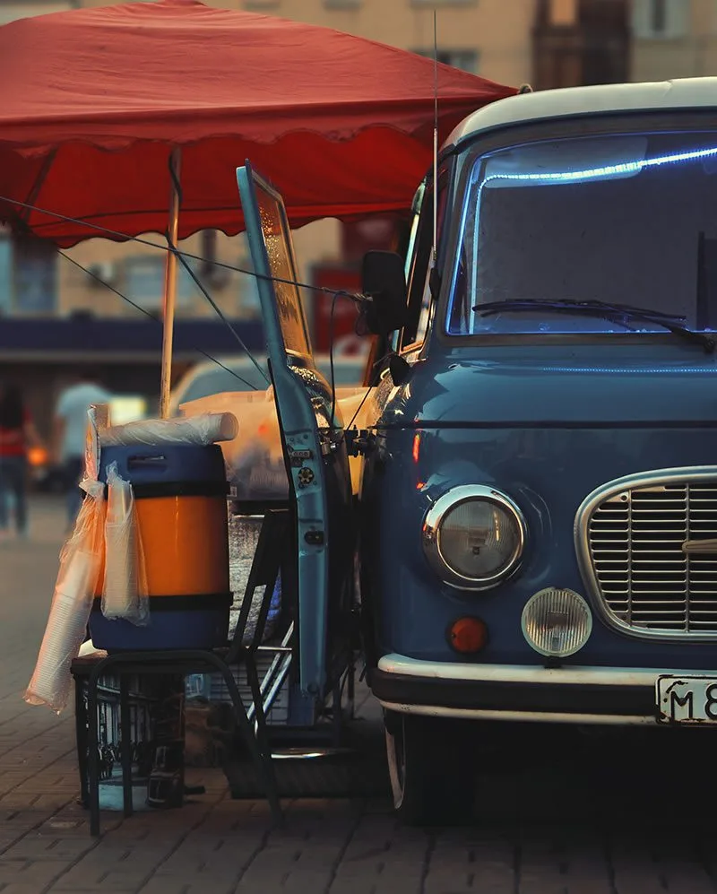 Blue food truck parked with a red canopy